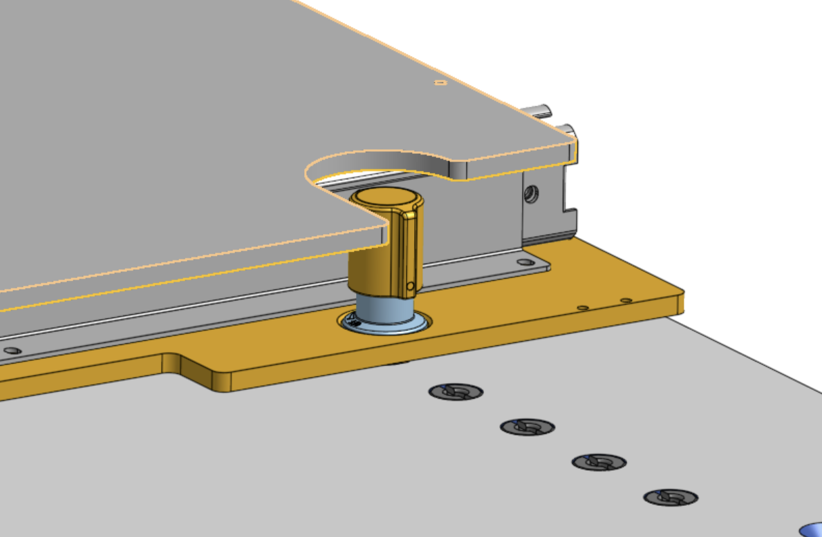 Close-up of a gray instrument plate whose U-shaped notch fits around a gold retractable knob on the yellow slide plate